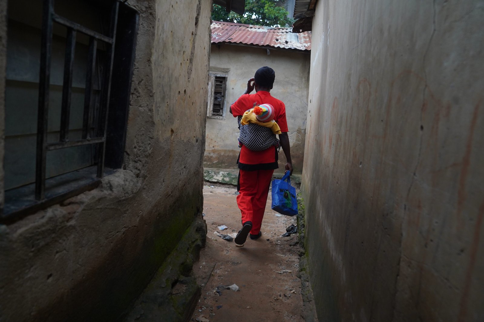 Kyuntu John walks toward the spot where she will board a motorcycle to the junction, from where she will take a cab to the Lugbe Primary Health Care Centre in Abuja, Nigeria, where she collects her antiretroviral therapy (ART) medication. July 29, 2025. Photograph: Marvellous Durowaiye /CCIJ