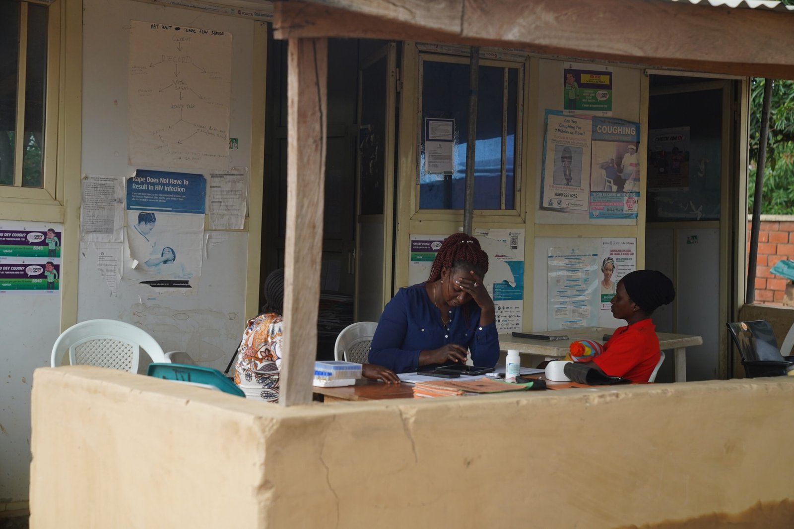 Tina Amos a Health care counsellor conduct a consultation with Kyuntu John outside a clinic adorned with informational posters at the Lugbe Primary Health Care Centre in Abuja, Nigeria. July 29, 2025. Photograph: Marvellous Durowaiye /CCIJ