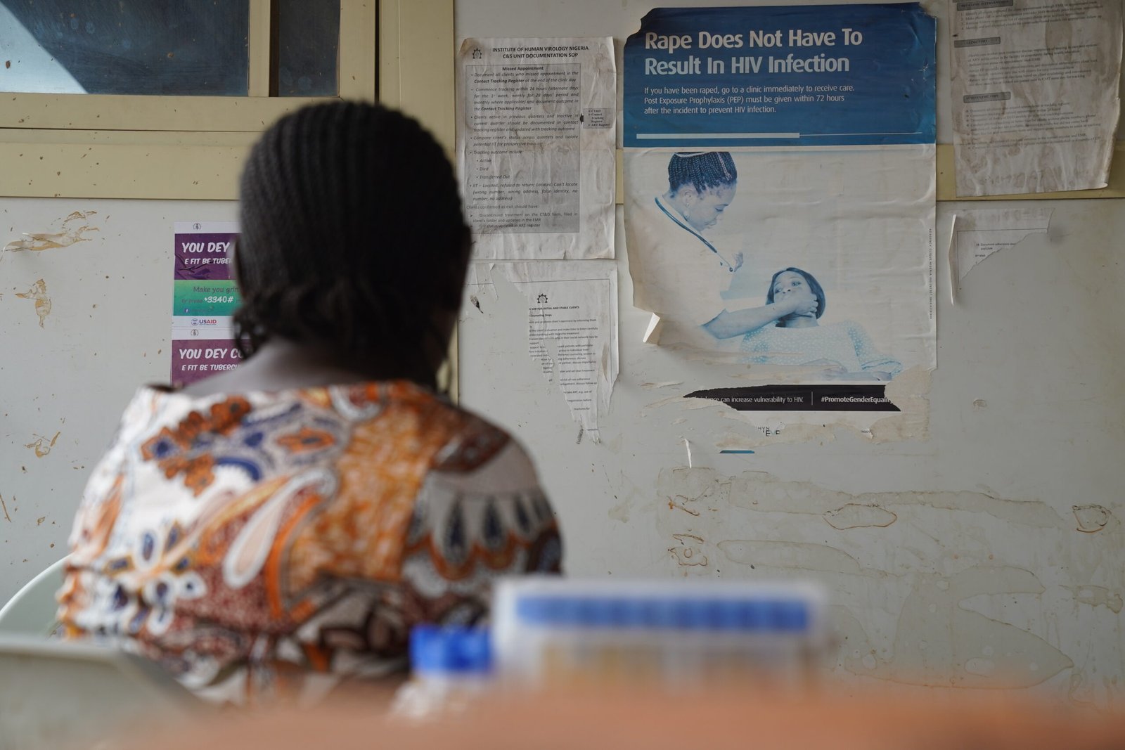 Blessing Benedict, a pregnant woman who came to collect her antiretroviral therapy (ART) medication, looks at a poster at the Lugbe Primary Health Care Centre in Abuja, Nigeria. July 29, 2025. Photograph: Marvellous Durowaiye /CCIJ