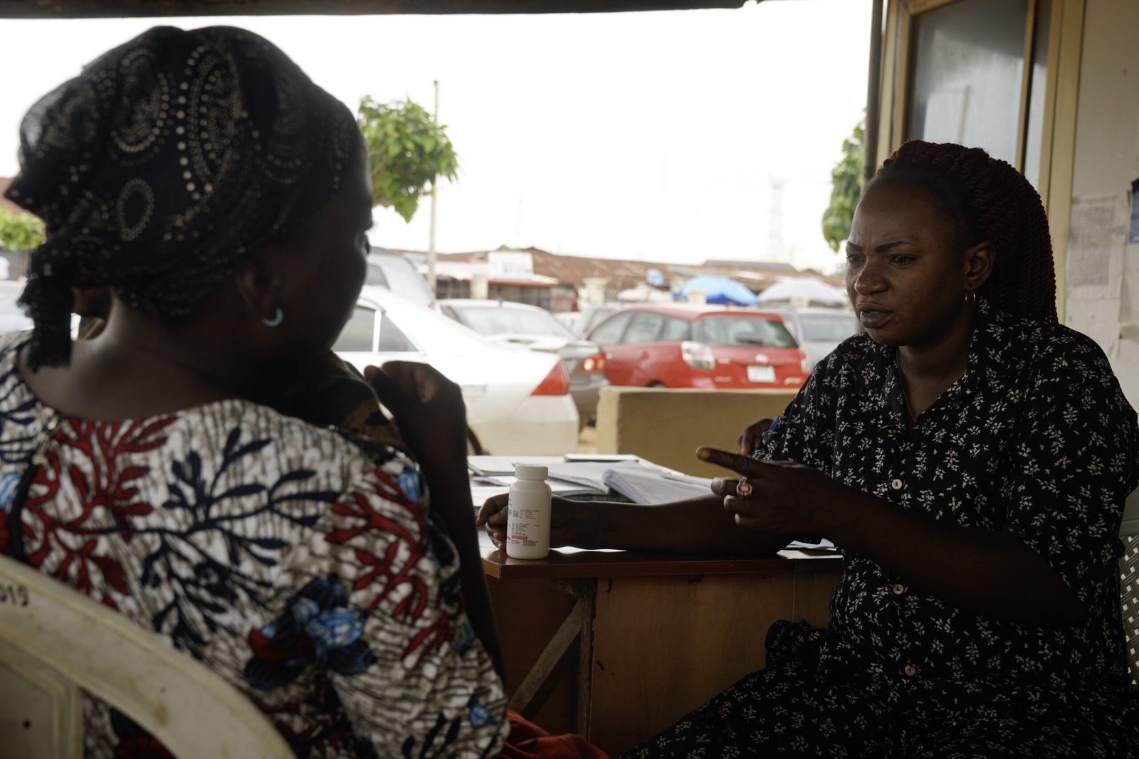 Tina Amos, a healthcare counsellor, reacts while speaking with Blessing Christopher during her visit to a health facility in Abuja, Nigeria, to collect her antiretroviral therapy (ART) drugs. July 30, 2025. Photograph: Marvellous Durowaiye /CCIJ
