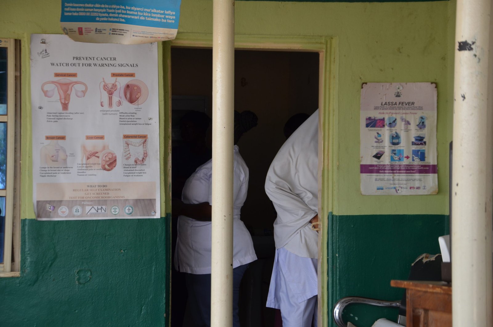 A permanent staff company with a voluntary staff standing by the door entrance at Damare PHC